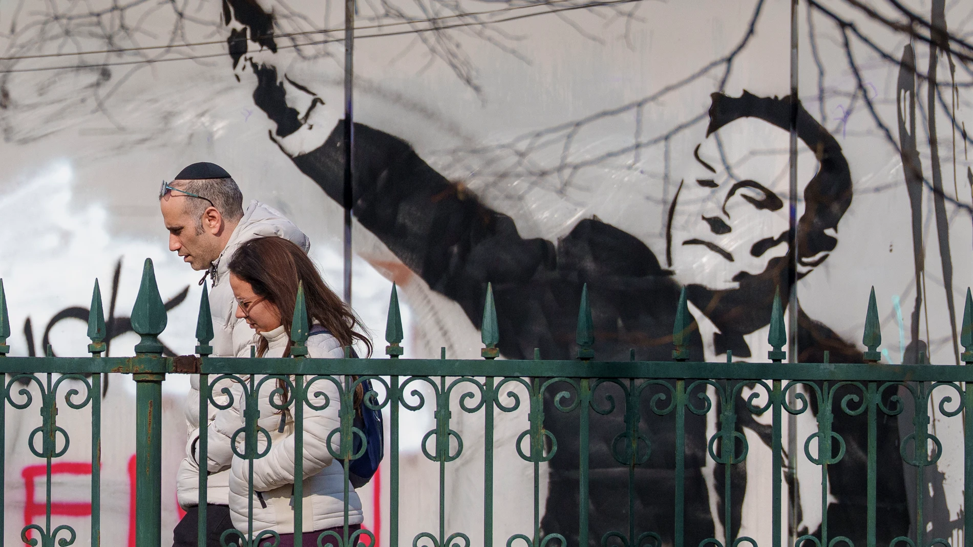 People walk by a graffiti depicting Elon Musk, in Bucharest, Romania, Monday, March 3, 2025. (AP Photo/Andreea Alexandru)