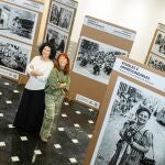 Las fotógrafas Ana Cortés y Pilar Cortés posan entre las imágenes de la exposición "Visibles e imprescindibles"