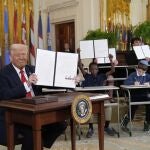 President Donald Trump, left, holds up a signed executive order as young people hold up copies of the executive order they signed at an education event in the East Room of the White House in Washington, Thursday, March 20, 2025. 