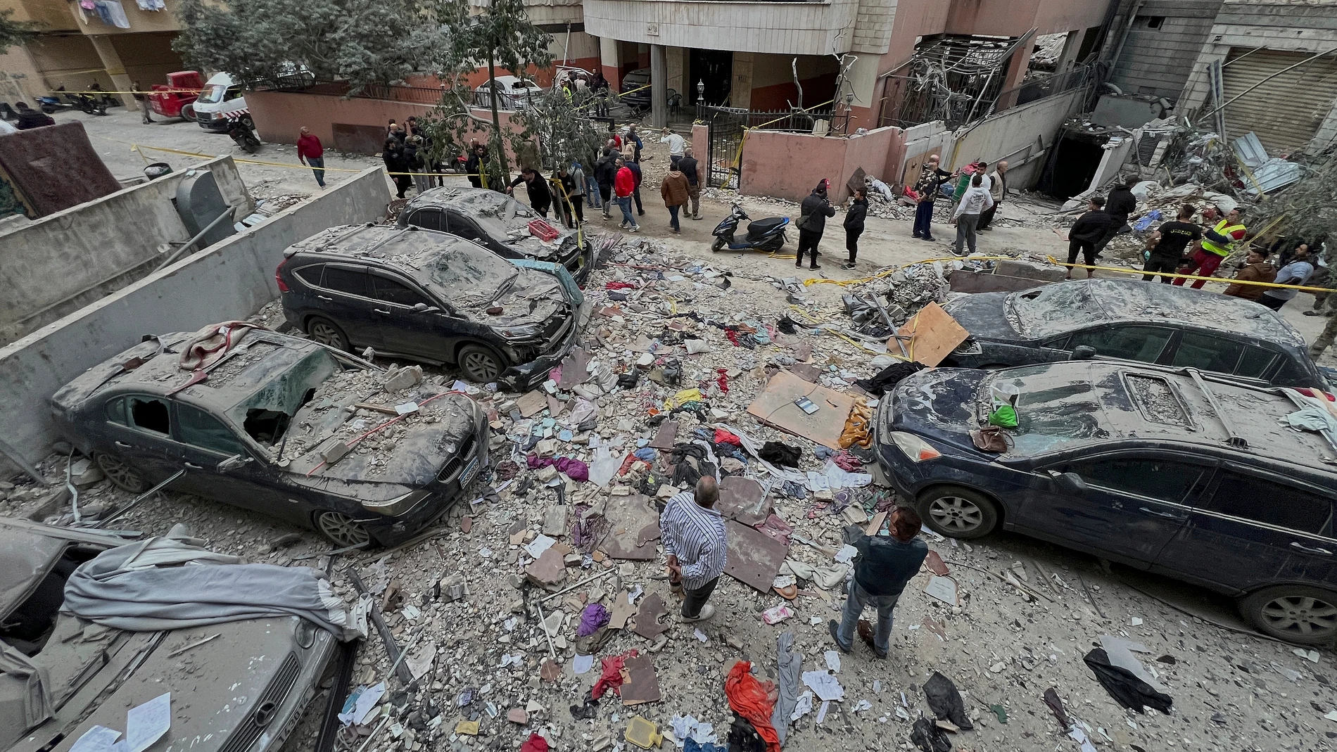 Lebanese residents gather around damaged cars at the site where an Israeli airstrike hit a building in Dahiyeh, a southern suburb of Beirut, Lebanon, early Tuesday, April 1, 2025. (AP Photo/Hussein Malla)