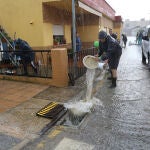Varias personas achican agua de sus viviendas tras una tormenta en la provincia de Palencia