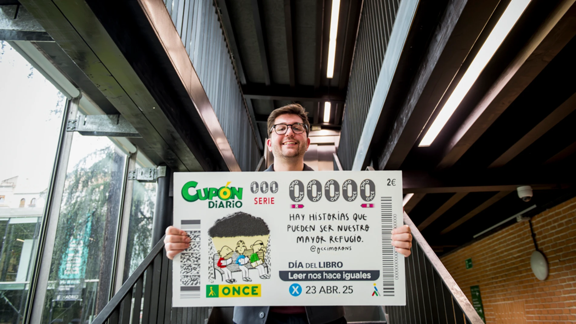 El ilustrador Pablo Rodríguez mostrando el diseño del cupón de la ONCE para El Día del Libro 2025.