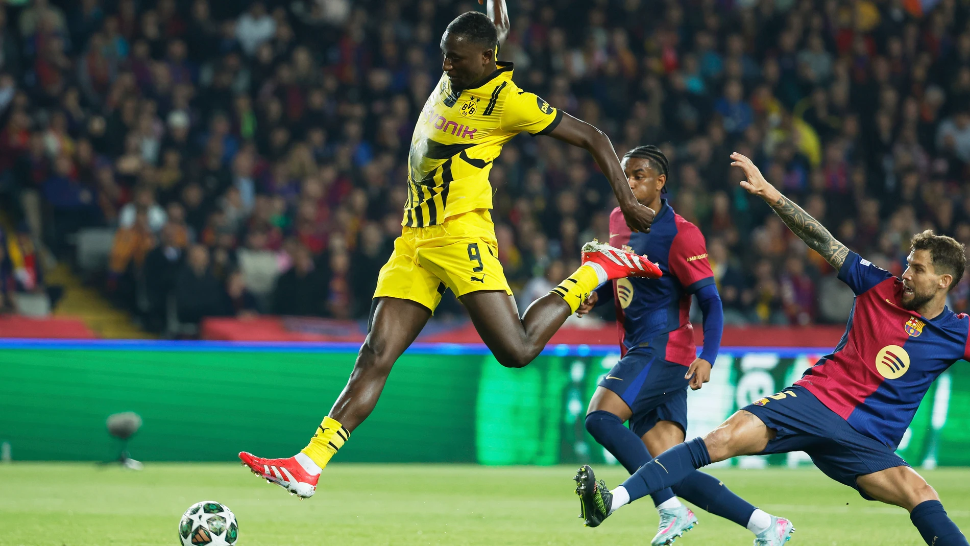 Dortmund's Serhou Guirassy, left, duels for the ball with Barcelona's Inigo Martinez, right, during the Champions League quarterfinals first leg soccer match between Barcelona and Borussia Dortmund, at the Lluis Companys Olympic stadium in Barcelona, Spain, Wednesday, April 9, 2025. (AP Photo/Joan Monfort)