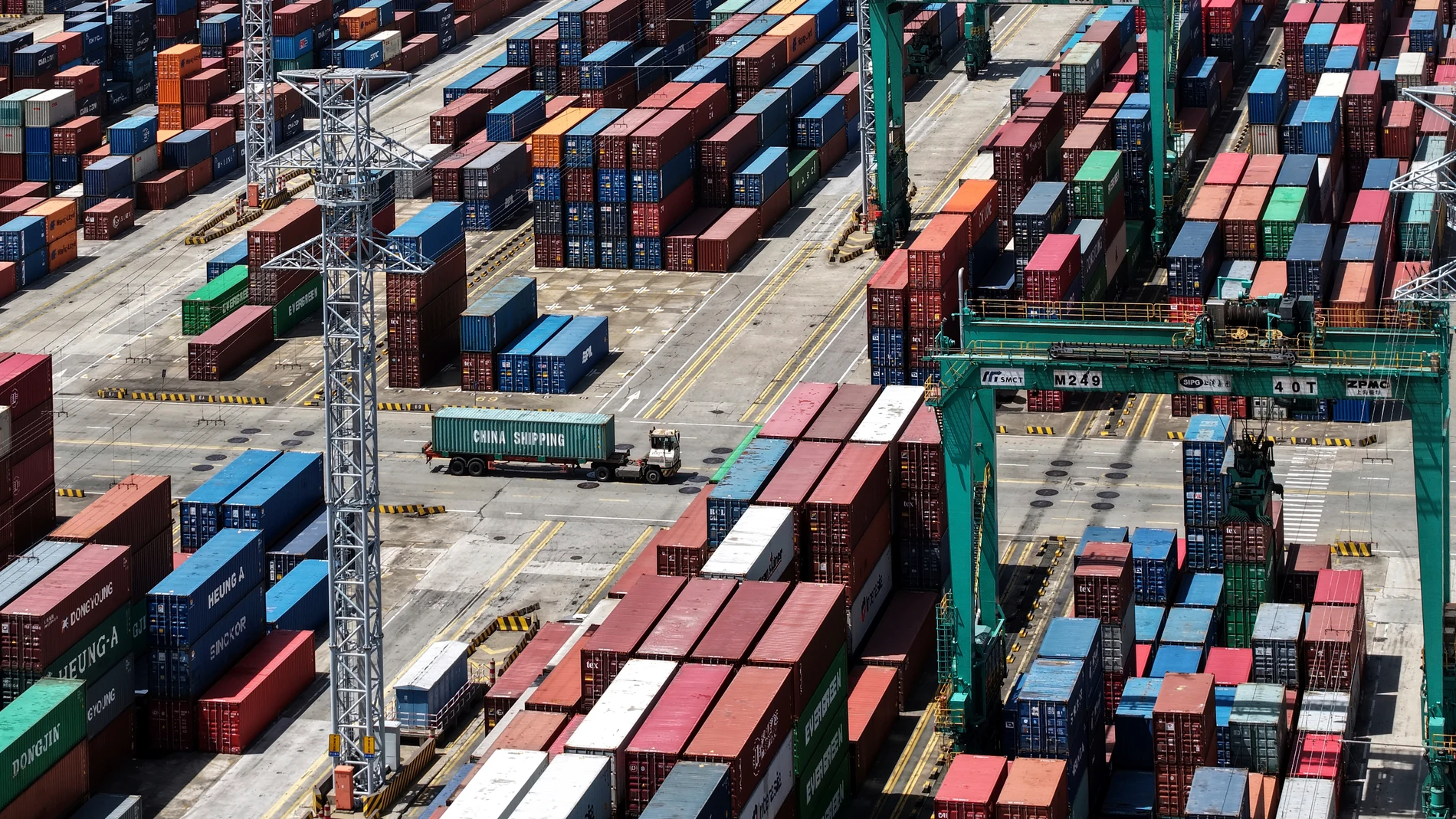 A truck moves past pile of containers store at a container terminal in Shanghai, China Sunday, April 13, 2025. (Chinatopix Via AP)