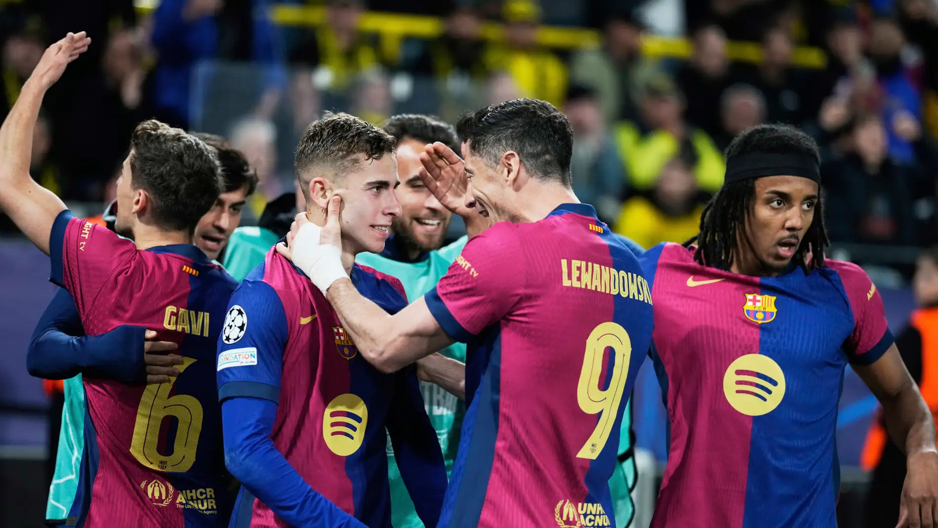 Barcelona's Robert Lewandowski (9) and Fermin Lopez celebrate after forcing an own goal by Dortmund's Ramy Bensebaini during the Champions League quarterfinals second leg soccer match between Borussia Dortmund and Barcelona, at the Signa-Iduna Park in Dortmund, Germany, Tuesday, April 15, 2025. (AP Photo/Matthias Schrader)