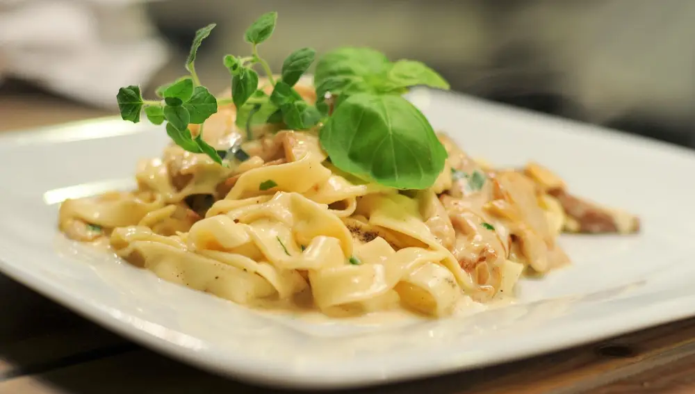 Plato de pasta a la carbonara con hojas de albahaca fresc