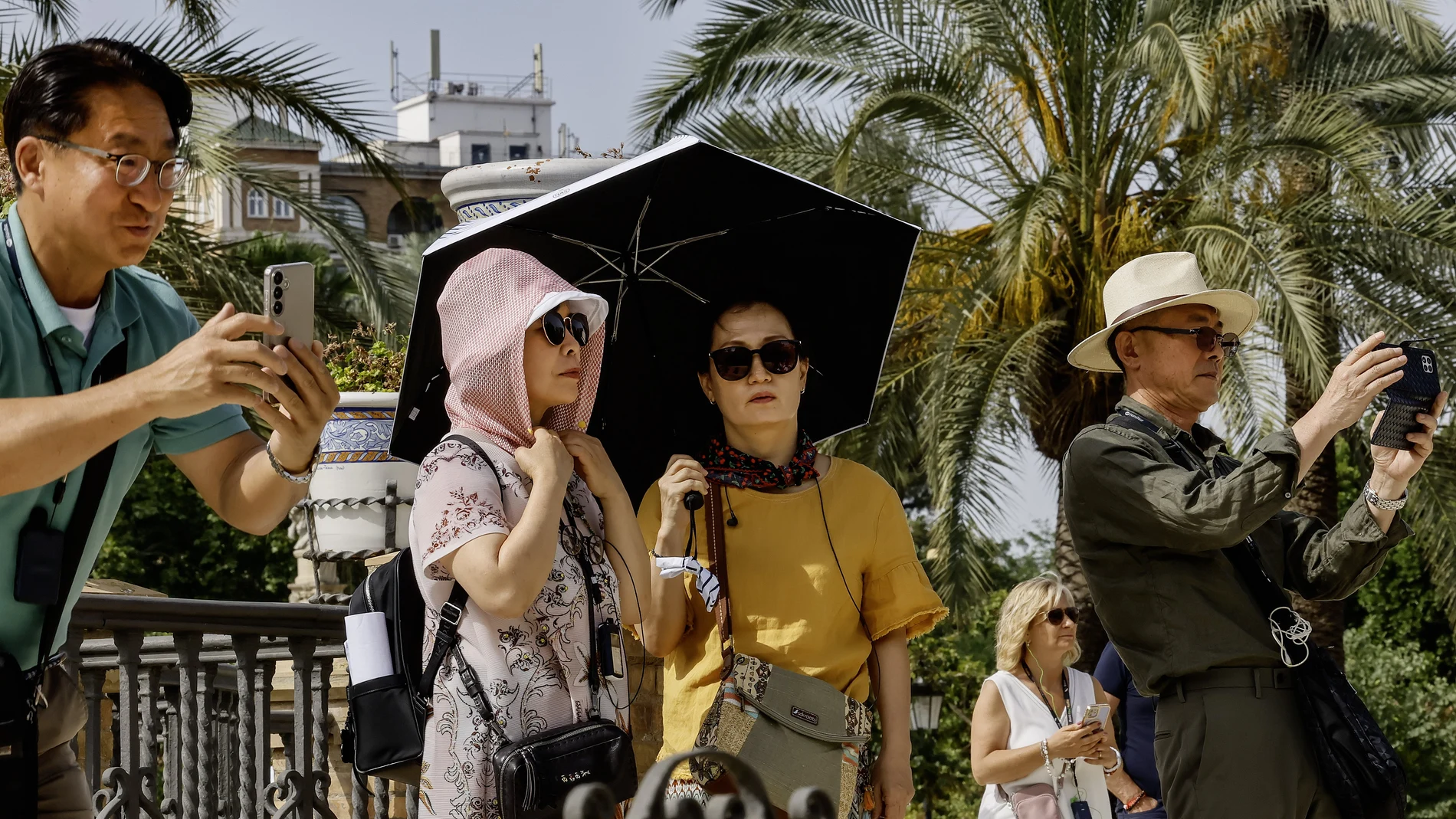 Turistas pasean protegidos con paraguas y pañuelos en la plaza de América de Sevilla, este viernes con temperaturas extremas de hasta 40 grados en Andalucía inusual para el último fin de semana de mayo.
