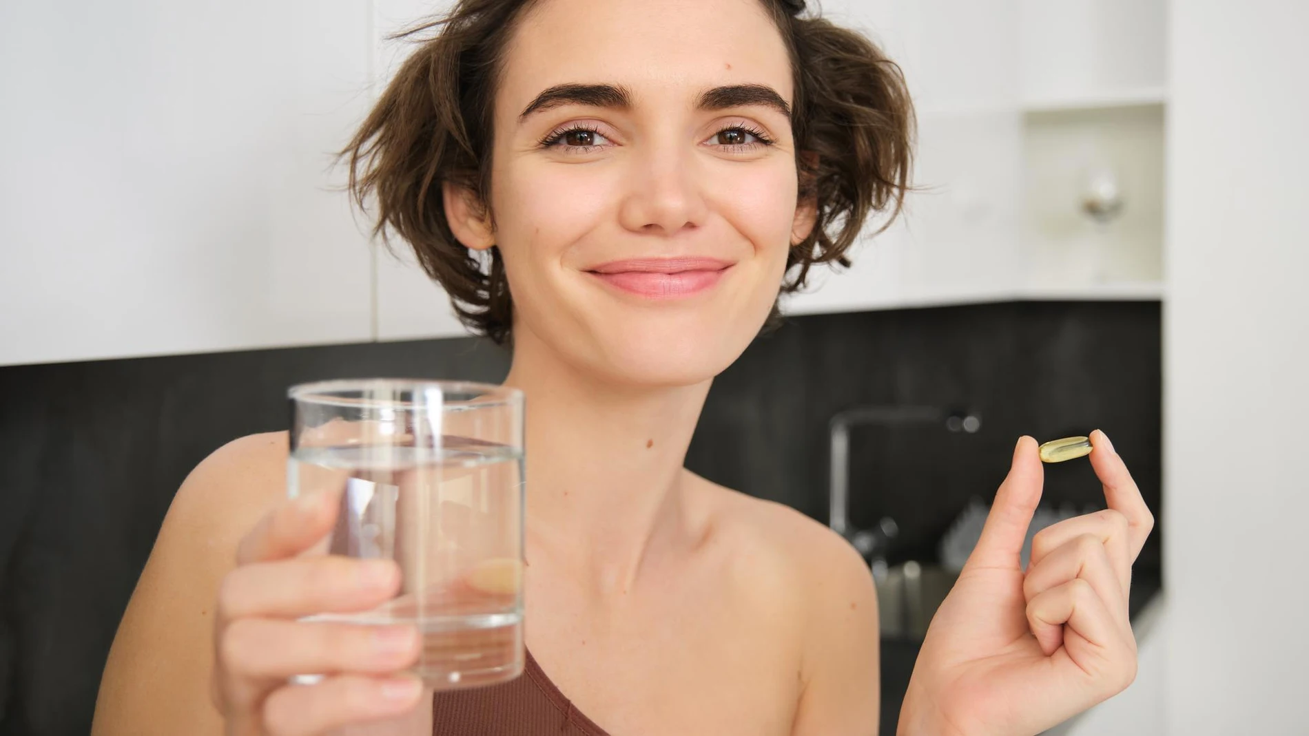 Mujer sostiene una vitamina D, agua, por sus beneficios para el envejecimiento