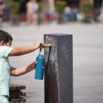 Un menor se refresca en una fuente