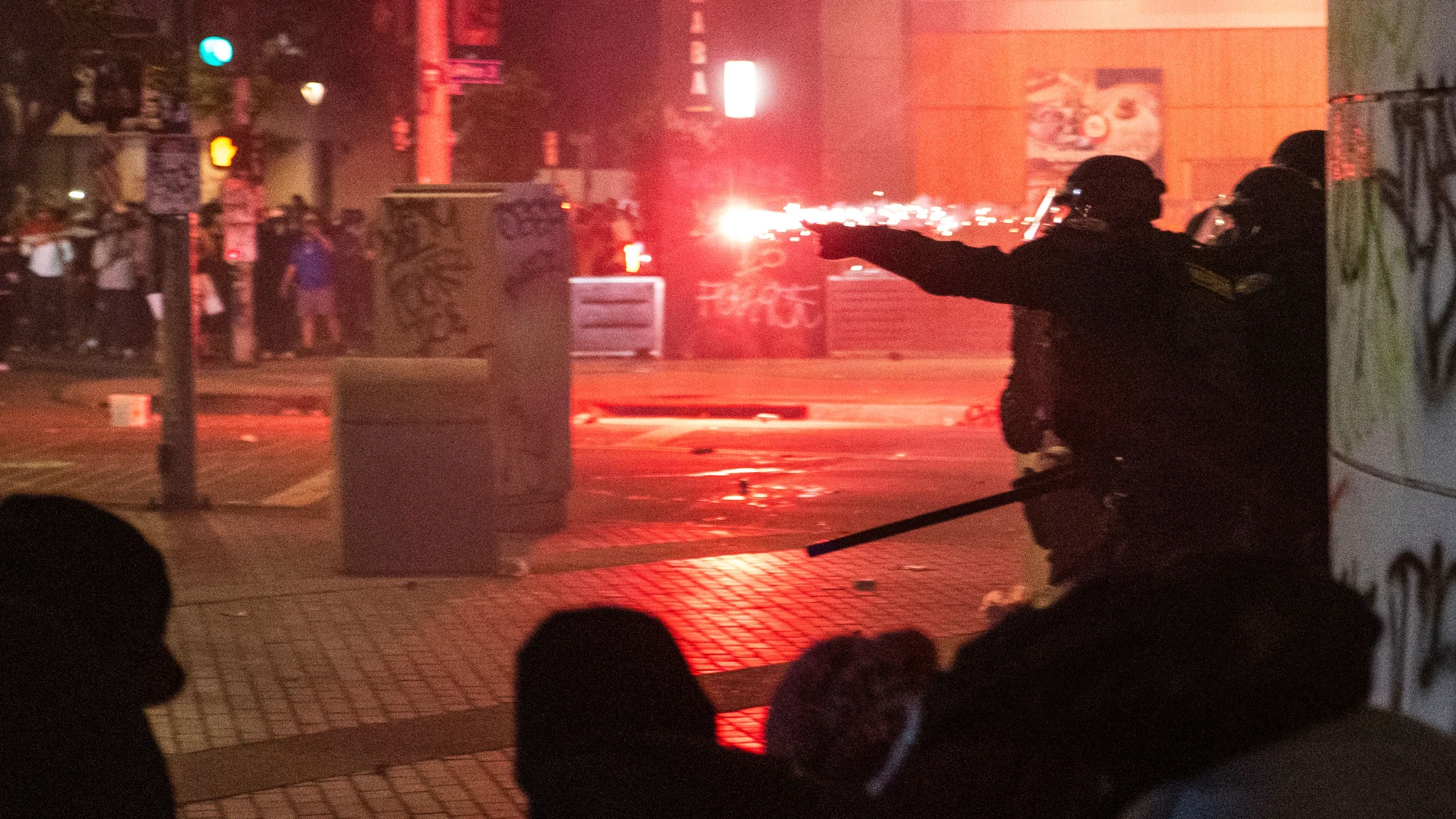 Police take cover from projectiles during protests over the Trump administration's immigration raids in Los Angeles, Monday, June 9, 2025. (AP Photo/Ethan Swope)