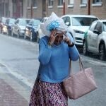 Una mujer se tapa la cabeza con una bolsa durante una fuerte tormenta en Valladolid
