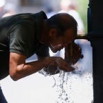 Un hombre refrescándose en una fuente. 