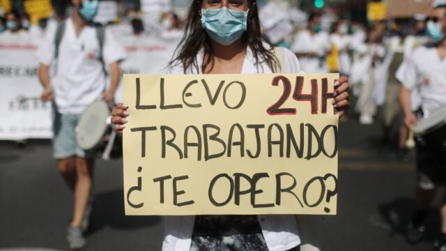 Una mujer sujeta una pancarta en la que se lee 'Llevo 24h trabajando, ¿te opero?' durante una manifestación de los médicos internos residentes (MIR) en Madrid 