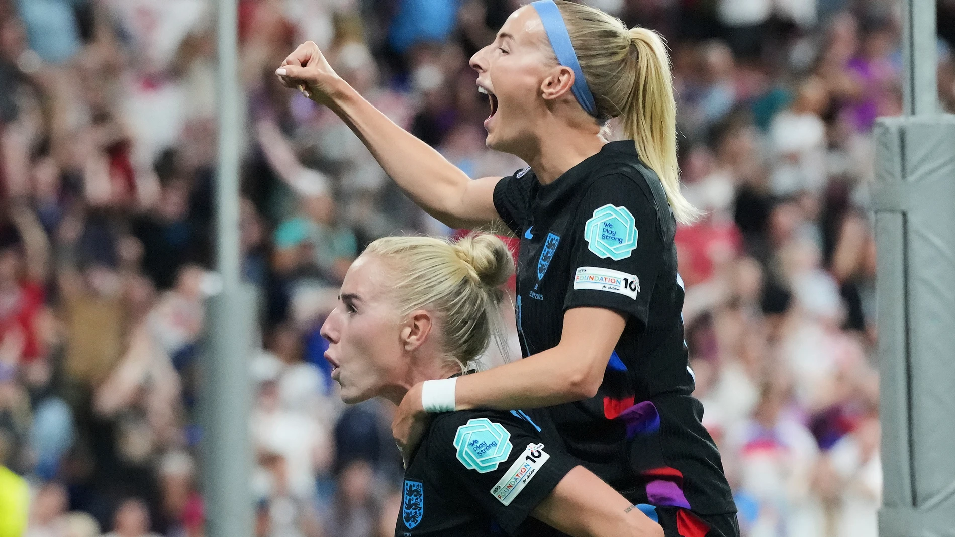 England's Chloe Kelly, up, celebrates on the back of England's Alex Greenwood after England scored their first goal during the Women's Euro 2025 semifinals soccer match between England and Italy at Stade de Geneve in Geneva, Switzerland, Tuesday, July 22, 2025. (AP Photo/Martin Meissner)