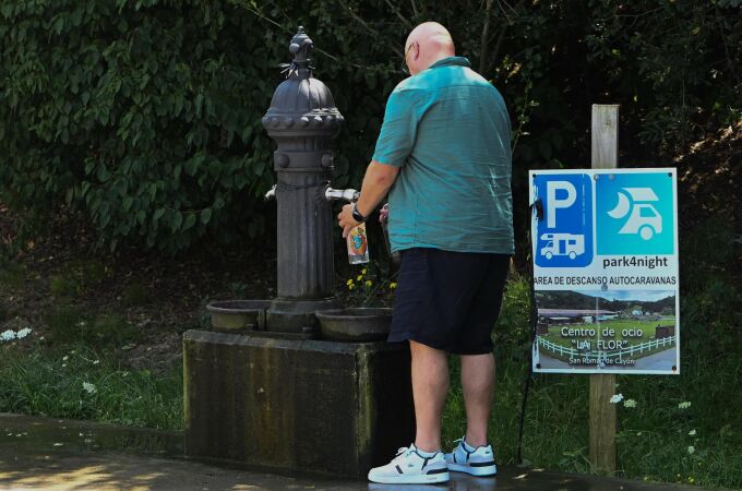 Un hombre refrescándose con el agua de una fuente. 