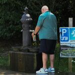 Un hombre refrescándose con el agua de una fuente. 
