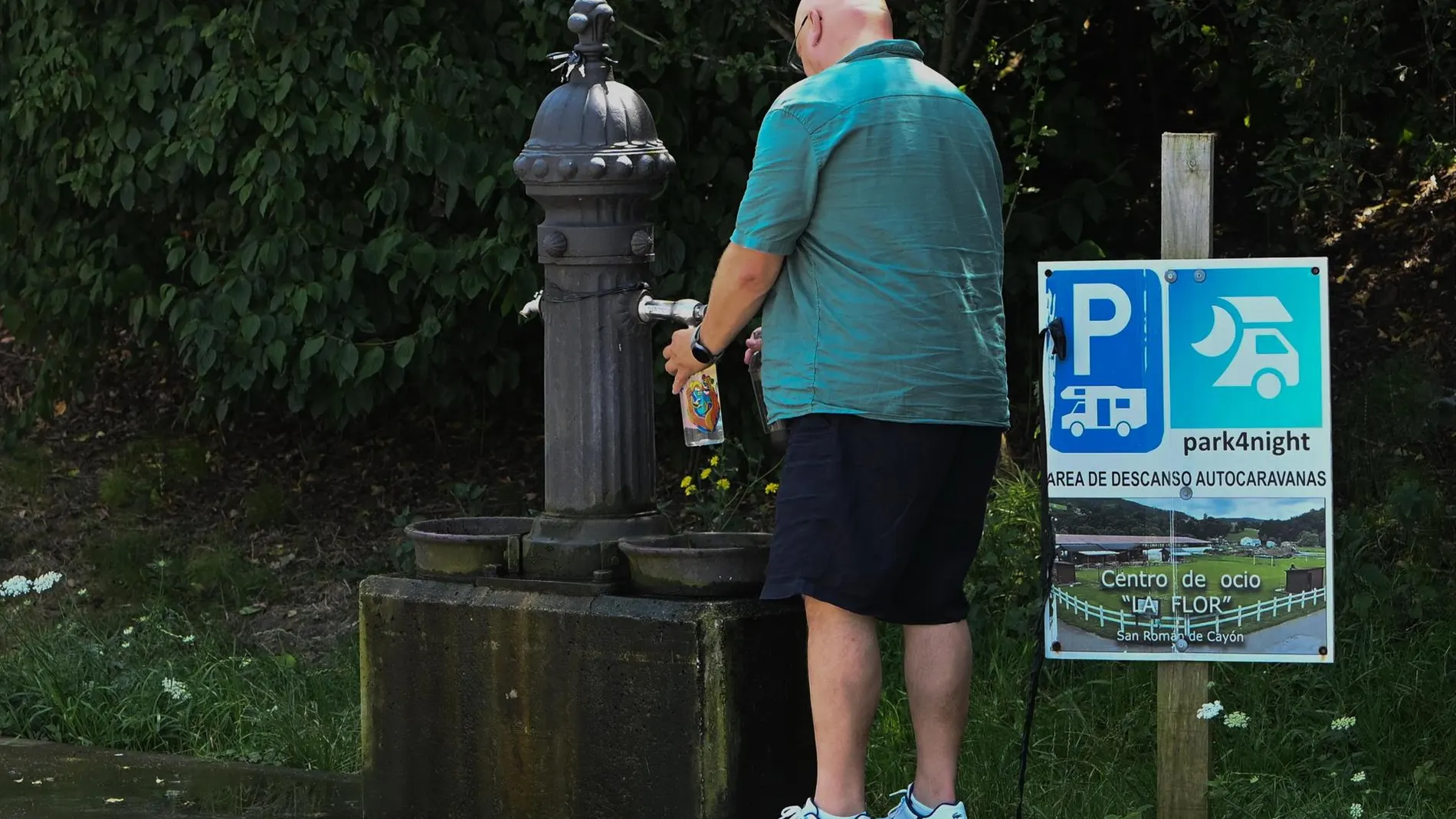 Un hombre refrescándose con el agua de una fuente.