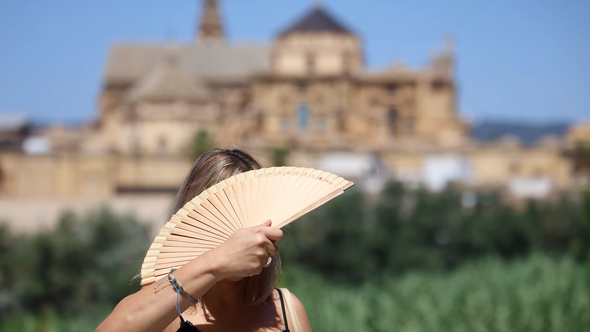 CÓRDOBA, 15/08/2025.- Una turista se abanica en el puente romano de Córdoba este viernes. El puente de agosto comienza con España inmersa en una larga ola de calor. EFE/ Salas