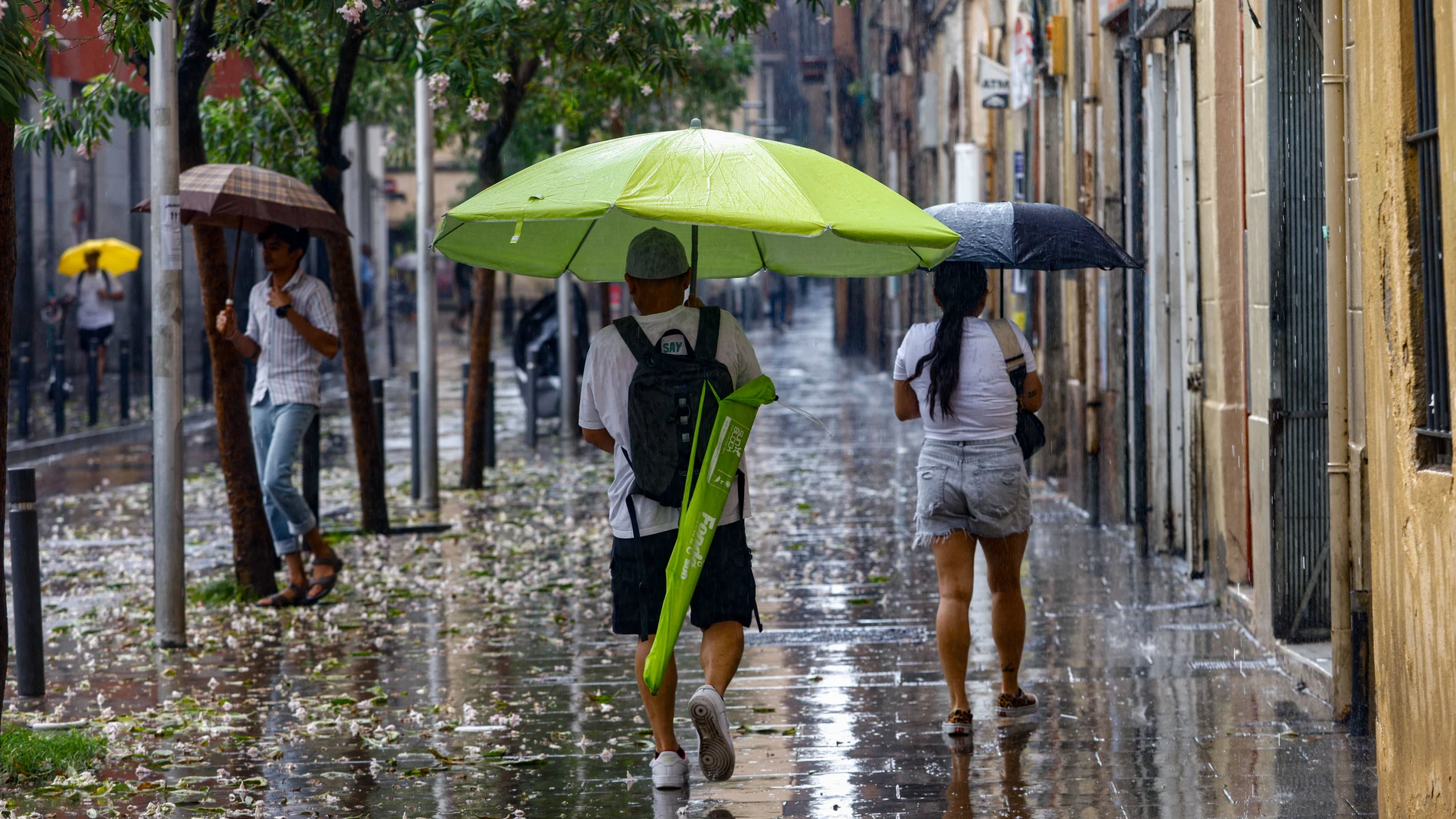 BARCELONA, 20/08/2025. -Una persona se protege con una sombrilla de playa de la tormenta caída a primera hora de la tarde en Barcelona, este miércoles, día en que Protección Civil de la Generalitat ha activado la alerta del plan INUNCAT ante la previsión de lluvias intensas a partir de las 14.00 horas de esta tarde y durante el día de mañana jueves en varios puntos del territorio. EFE/ Quique García