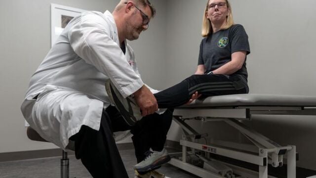 Matthew Beal, médico ortopédico examinando la cadera de un paciente en consulta