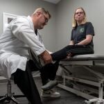 Matthew Beal, médico ortopédico examinando la cadera de un paciente en consulta