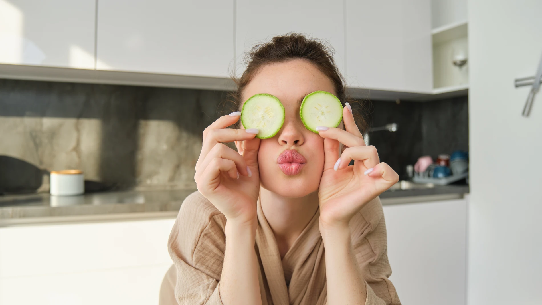 Mujer joven con rodajas de pepino sobre los ojos como remedio casero de belleza