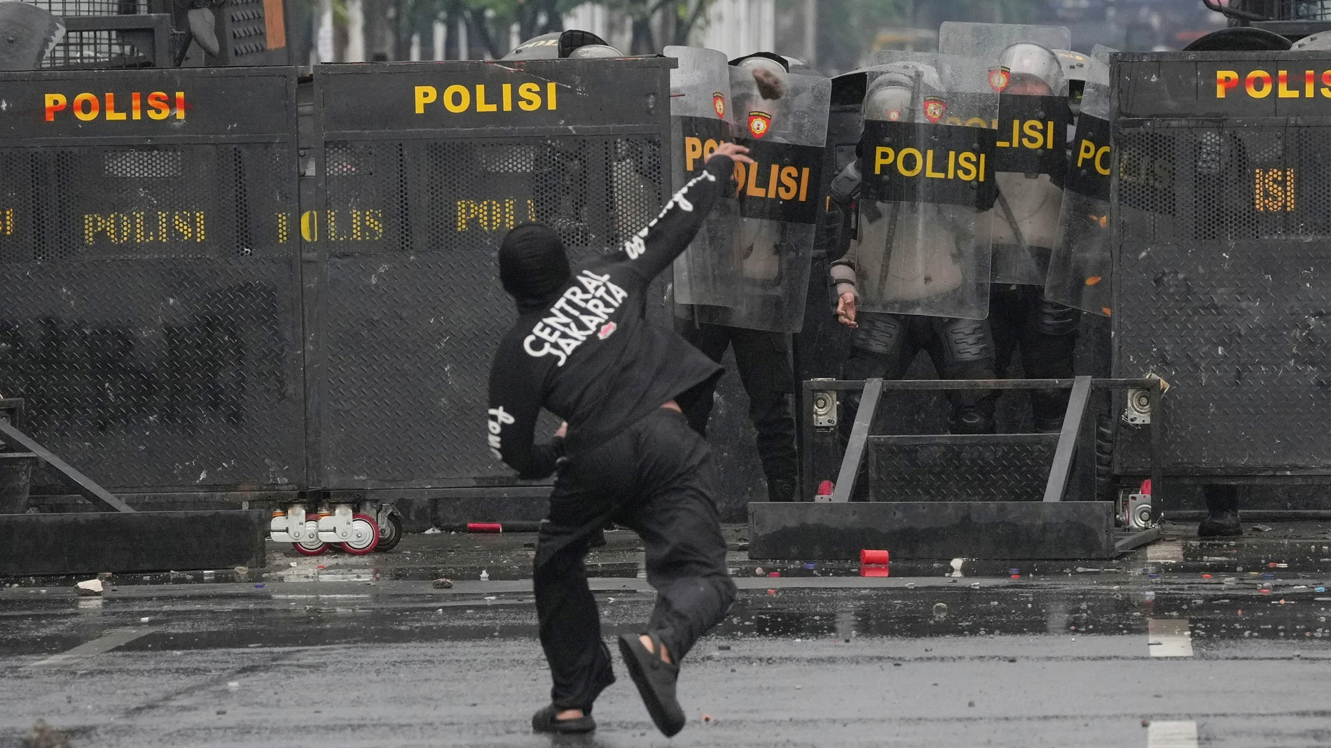 Policías indonesias se protegen de las piedras lanzadas por los manifestantes en Yakarta
