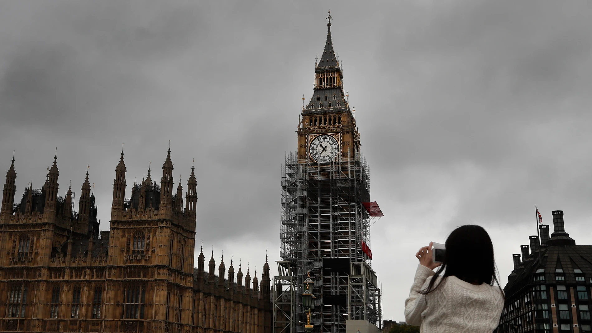 FILE - A woman takes a picture of parliament as scaffolding stands around the London landmark, almost up to the clock face, in London, Wednesday, Oct. 11, 2017. (AP Photo/Kirsty Wigglesworth, File)