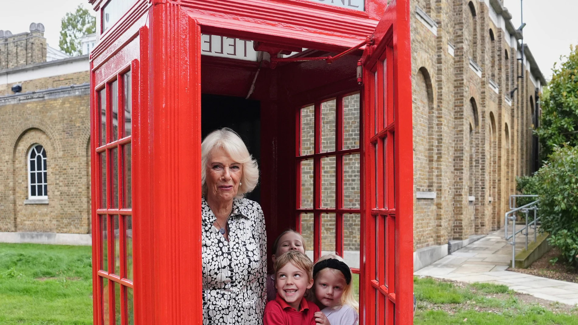 Britain's Queen Camilla joins eight pupils from Dulwich Village Infants' School inside the original telephone box during her visit to Dulwich Picture Gallery in south-east London, Thursday Sept. 4, 2025. (Jonathan Brady/PA via AP, Pool)