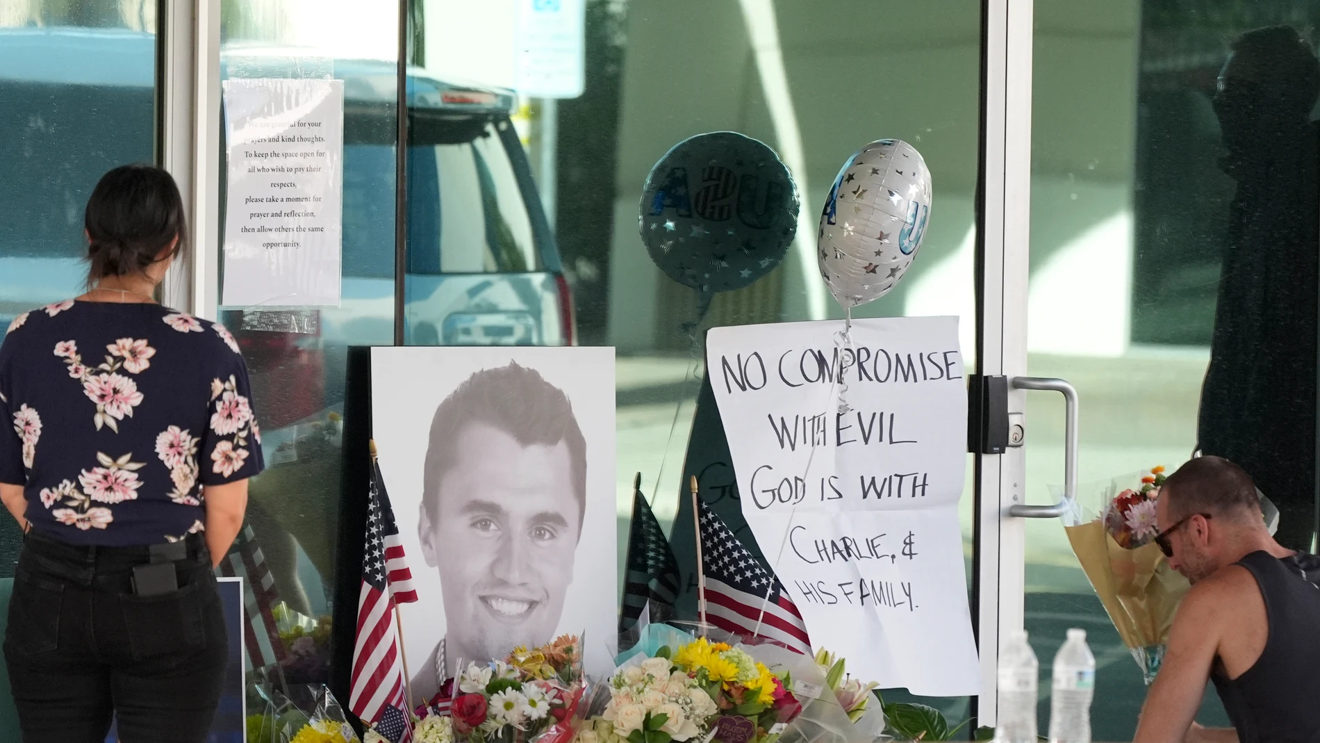 Well-wishers pay their respects at a makeshift memorial at the national headquarters of Turning Point USA shown after the shooting death of Charlie Kirk, the co-founder and CEO of the organization, during a Utah college event Wednesday, Sept. 10, 2025, in Phoenix. (AP Photo/Ross D. Franklin)