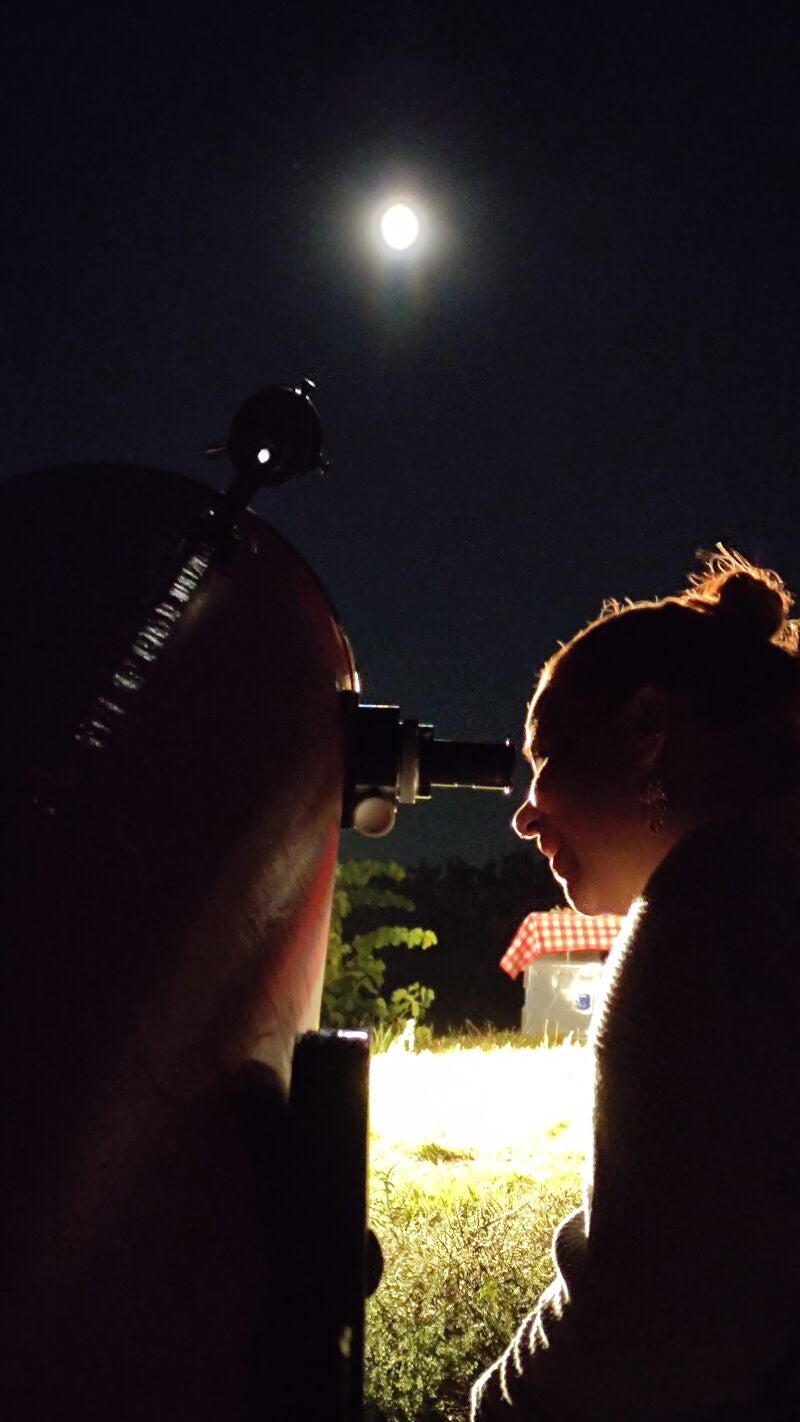 Una mujer observa el cielo por un telescopio durante una cata de estrellas organizada por Bodega La Olmilla