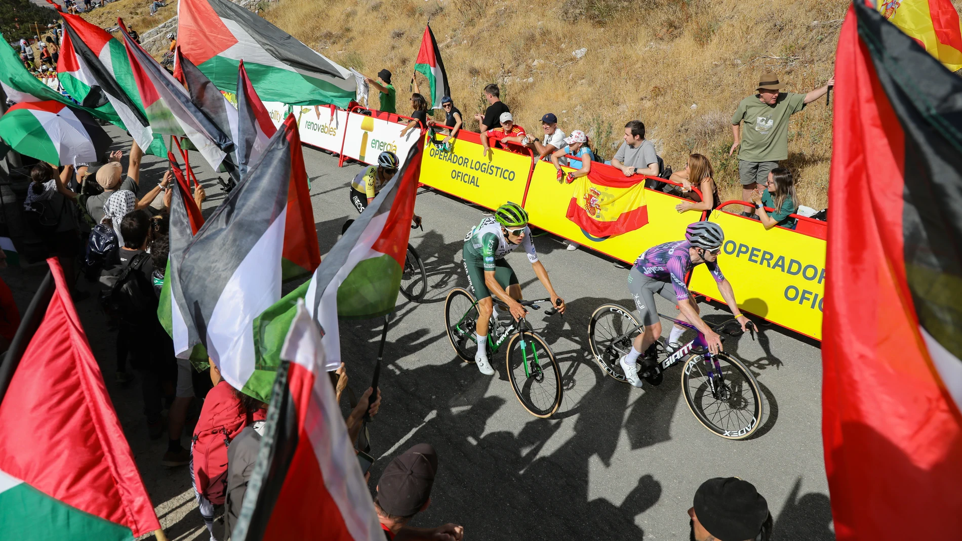 Varios ciclistas pasan por una zona con protestas propalestinas durante la 20ª etapa de la Vuelta Ciclista a España, a 13 de septiembre de 2025, en Navacerrada, Madrid (España). Las protestas contra el equipo Israel Premier Tech en la Vuelta a España han causado cortes, suspensiones y decenas de detenidos. Incidentes relevantes llevaron a cancelar la etapa 11 y a interrumpir otras por seguridad. El equipo israelí tuvo que retirar su nombre del maillot para reducir la tensión. A pesar de todo,...