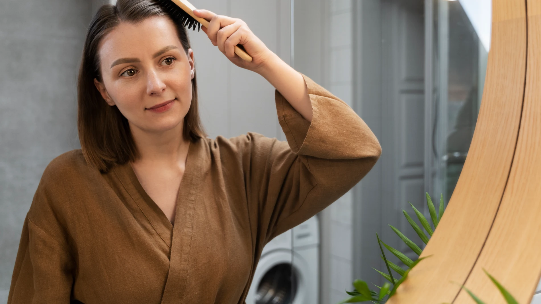 Cuidado cotidiano del cabello en otoño, mujer peinándose frente al espejo.