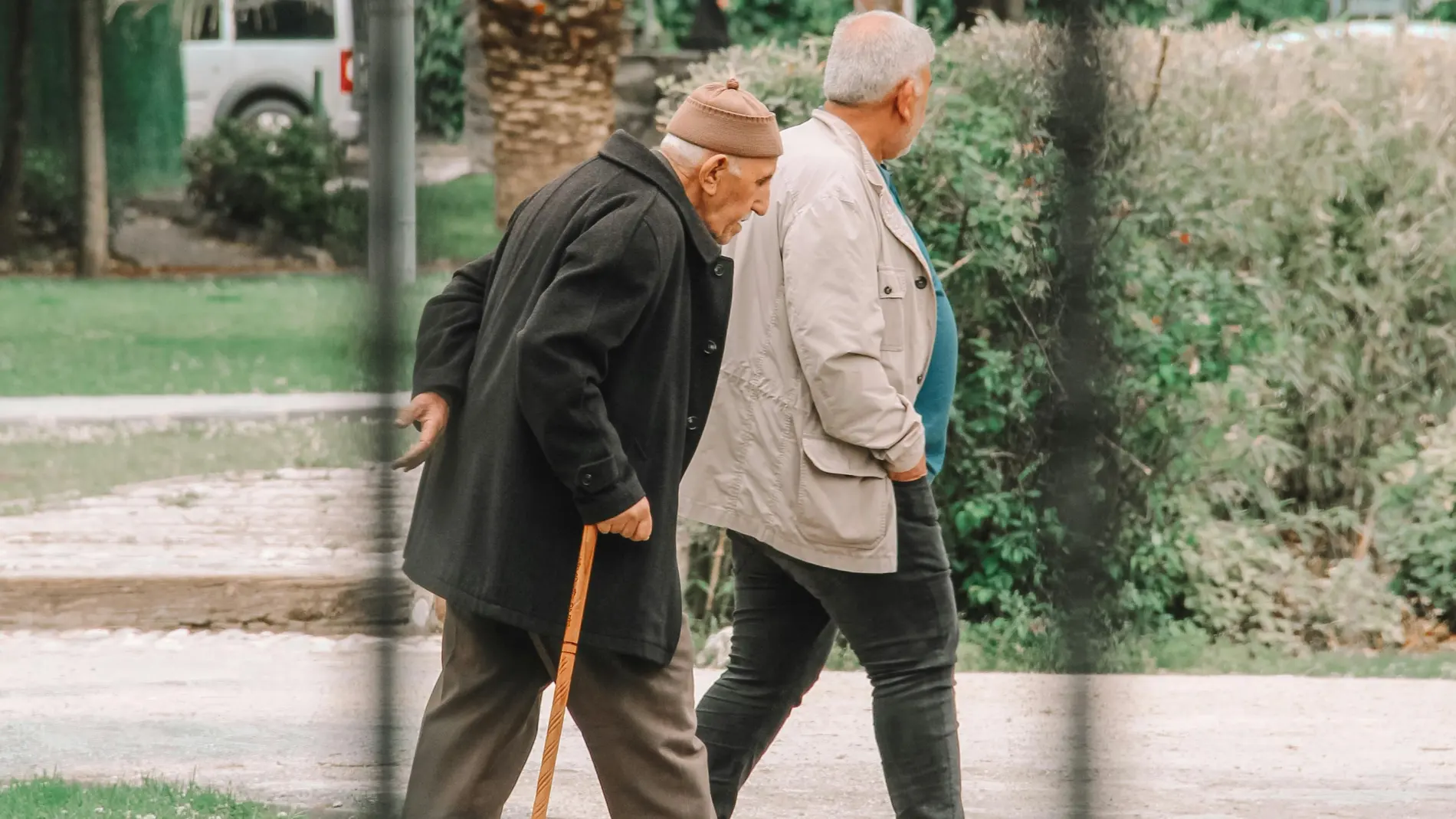 Anciano encorvado tocándose la espalda con dolor
