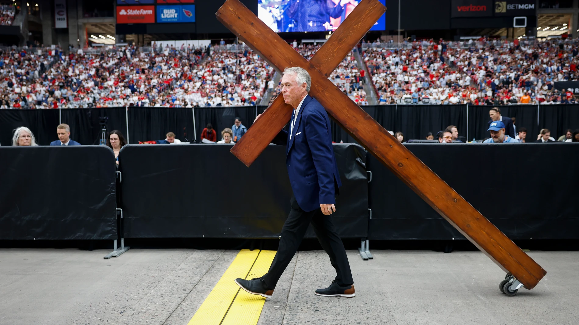 GLENDALE (USA), 21/09/2025.- Dan Beasley carries a wooden cross through State Farm Stadium ahead of the public memorial service of political activist Charlie Kirk in Glendale, Arizona, USA, 21 September 2025. Kirk was shot and killed on 10 September during a stop on his American Comeback Tour organized by Turning Point USA at Utah Valley University. EFE/EPA/CAROLINE BREHMAN