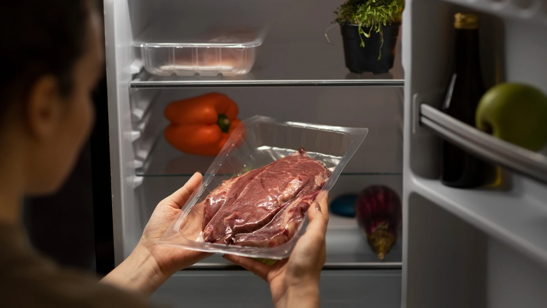 Una mujer saca de la nevera una carne de pollo que no debe guardarse más de un día en la nevera