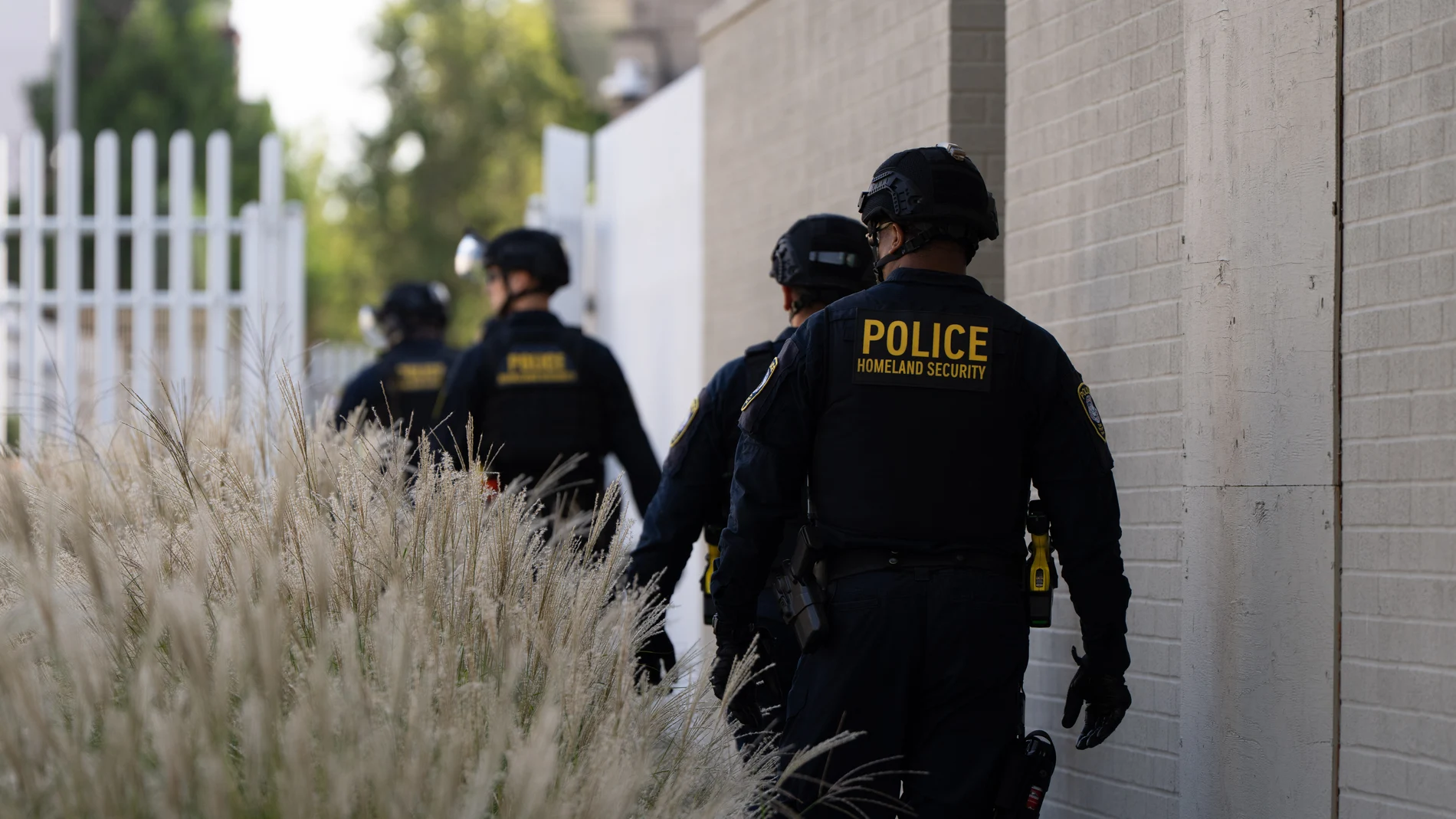 Department of Homeland Security officials walk to the gates of the U.S. Immigration and Customs Enforcement facility after inspecting an area outside on Sunday, Sept. 28, 2025, in Portland, Ore. (AP Photo/Jenny Kane)
