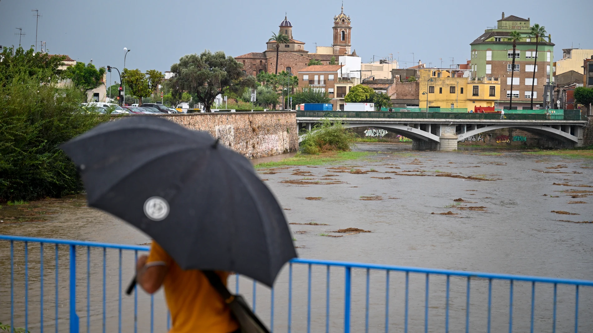 GRAFCVA9475. BURRIANA (CASTELLÓN), 29/09/2025.- Una persona cruza un puente sobre el río Ana durante este lunes en el que el aviso rojo (riesgo extremo) por precipitaciones que pueden acumular 180 litros por metro cuadrado en doce horas estará activo hasta la medianoche de hoy en el litoral de la provincia de Valencia, mientras que ha finalizado en el litoral norte de Castellón este mediodía. EFE/Andreu Esteban