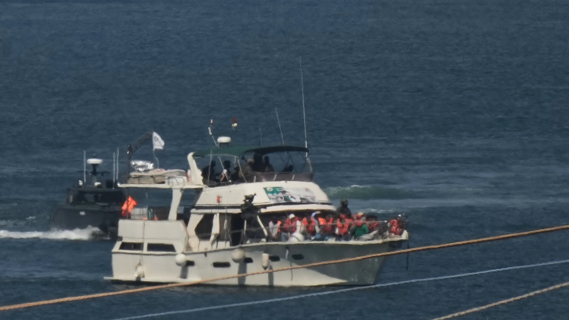 Activists in orange life jackets sit aboard a Gaza-bound Sumud flotilla boat as Israeli navy soldiers sail it into Ashdod, Israel, Thursday, Oct. 2, 2025, after it was intercepted off the Gaza coast. (AP Photo/Leo Correa)