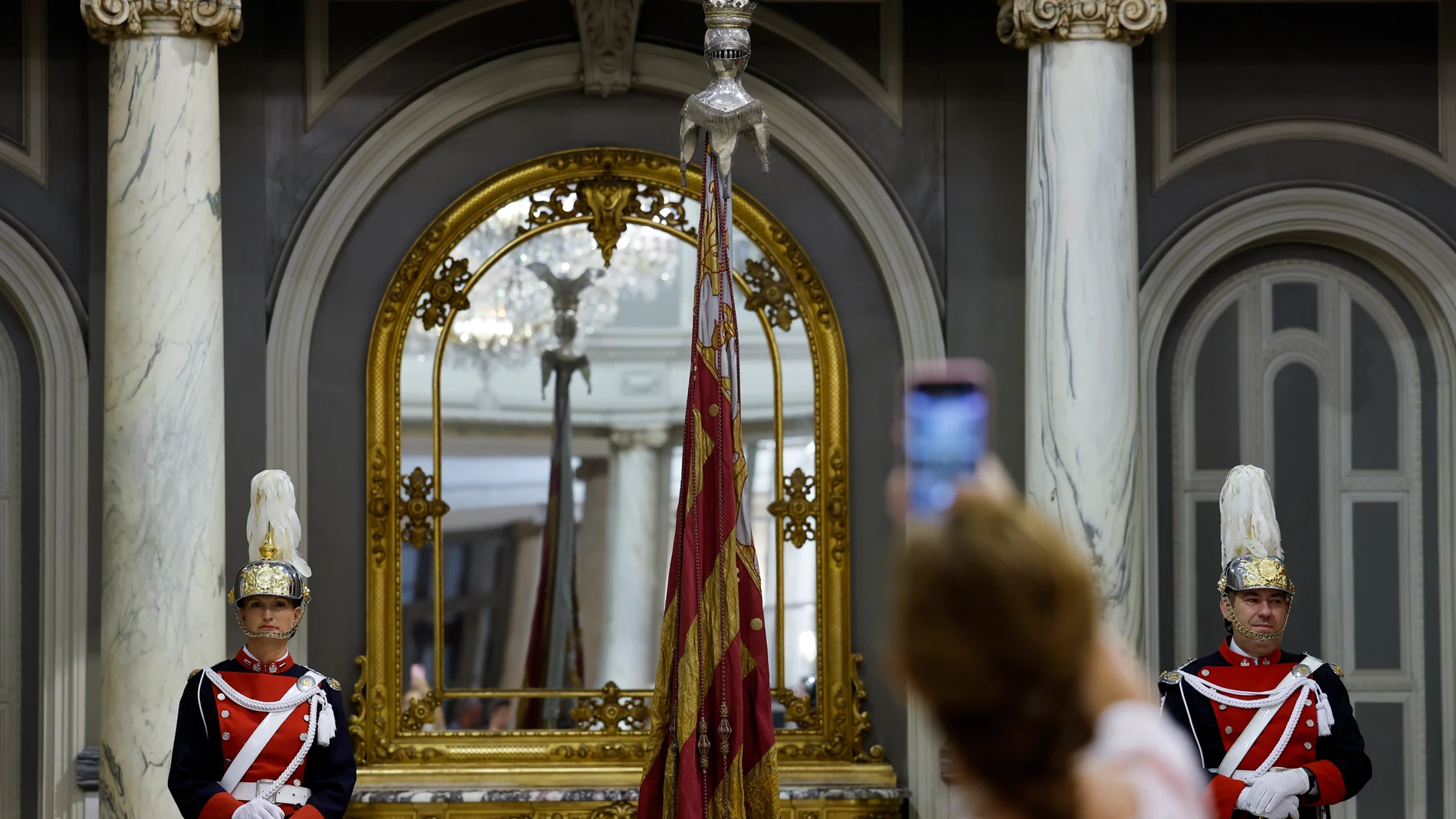 GRAFCVA9693. VALENCIA, 08/10/2025.- Una persona toma una imagen de la Real Senyera expuesta en el Salón de Cristal del ayuntamiento con motivo de la exposición “La Nostra Senyera”. EFE/Ana Escobar
