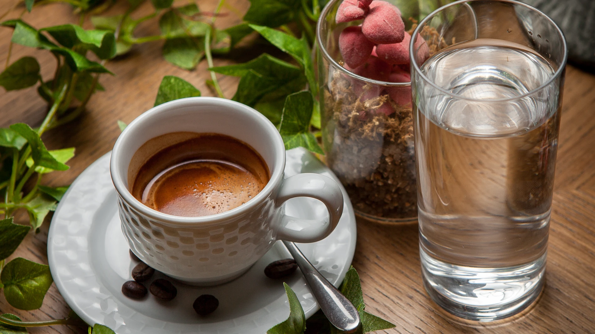 Café y té junto a un vaso de agua sobre una mesa, concepto de hidratación y longevidad