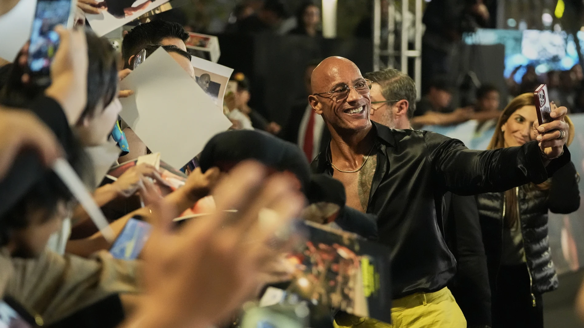 Actor Dwayne Johnson takes a selfie with fans during a red carpet event for the film "The Smashing Machine" in Mexico City, Tuesday, Oct. 7, 2025. (AP Photo/Claudia Rosel)