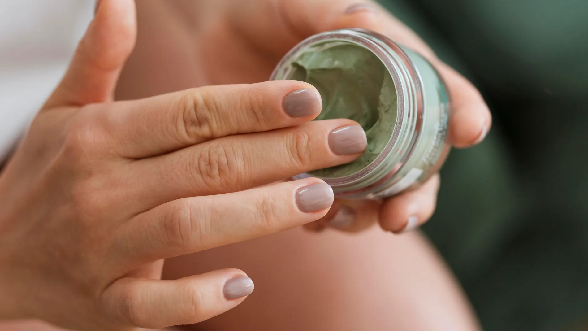 Mano de mujer tomando crema antes de aplicarla