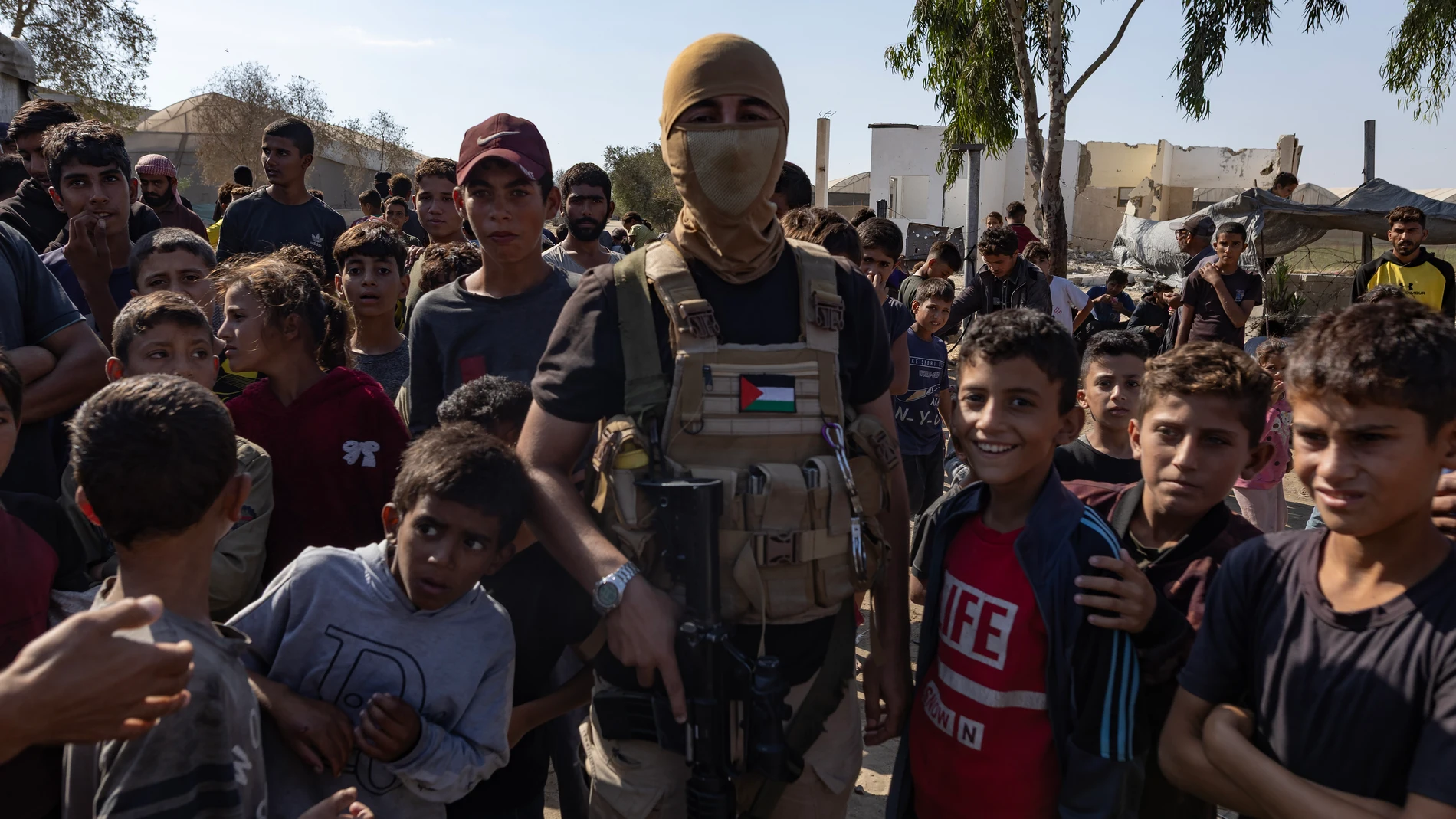 Un combatiente de las Brigadas Al-Qassam se encuentra con palestinos tras la entrega de rehenes israelíes al Comité Internacional de la Cruz Roja (CICR) en el sur de Deir al-Balah, en el centro de la Franja de Gaza