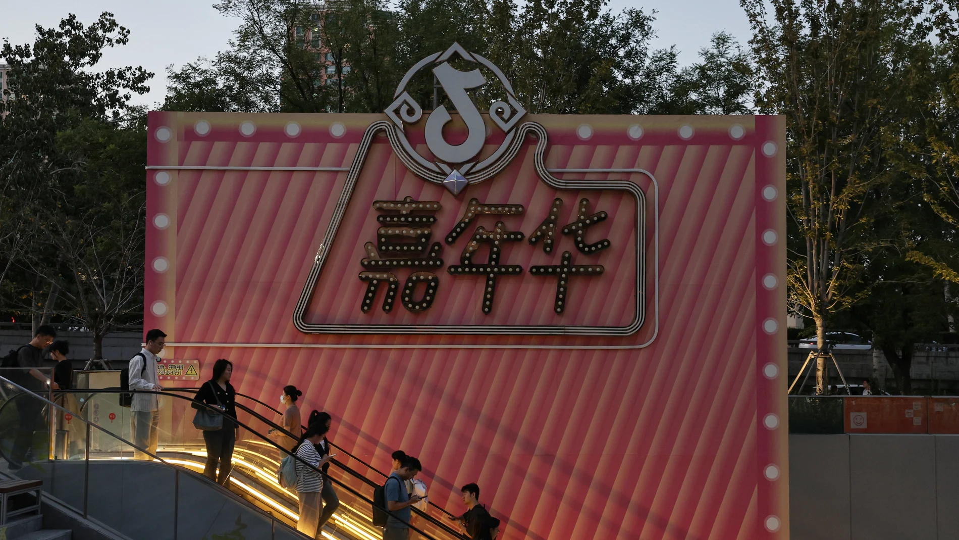 People ride an escalator next to a Douyin logo in Beijing, China. The Douyin app is the Chinese counterpart of TikTok.