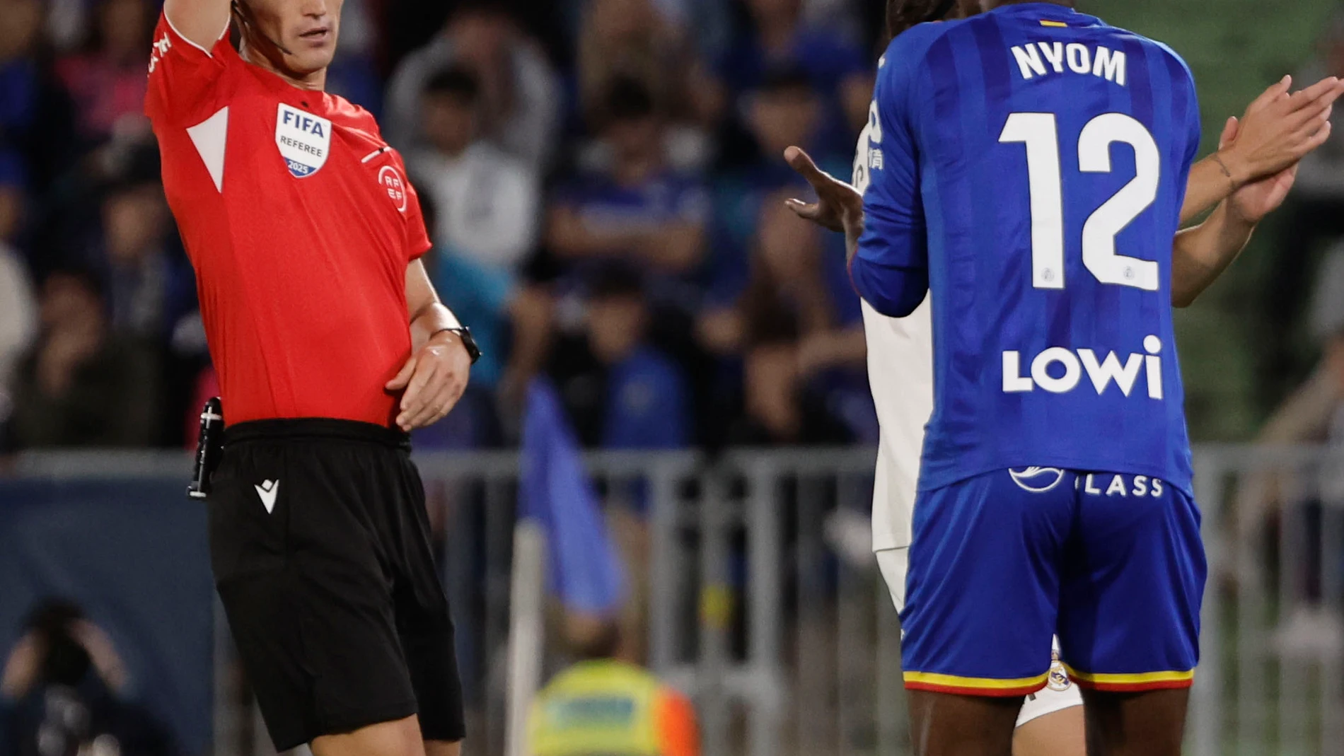 GETAFE (COMUNIDAD DE MADRID), 19/10/2025.- El colegiado Munuera Montero expulsa al defensa camerunés del Getafe, Allan Nyom, durante el partido de la jornada 9 de LaLiga EA Sports que Getafe y Real Madrid disputan hoy domingo en el Coliseum, en Getafe (Comunidad de Madrid). EFE/Sergio Perez.