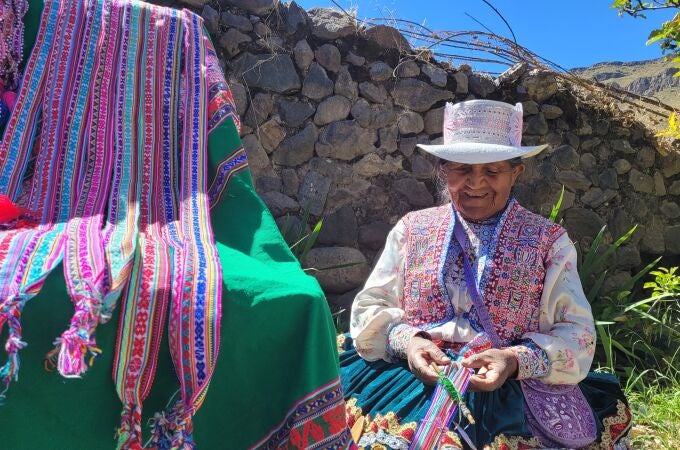 Una mujer realiza obras de artesania, ataviada con el traje típico Una mujer realiza obras de artesania, ataviada con el traje típico