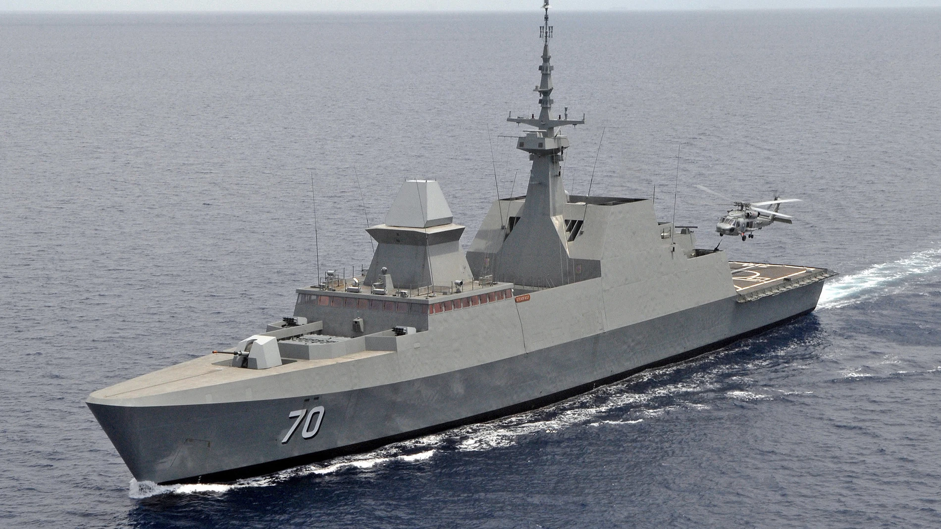 Navío de color metalizado con el número 70 navegando en alta mar mientras un helicóptero despega de la popa