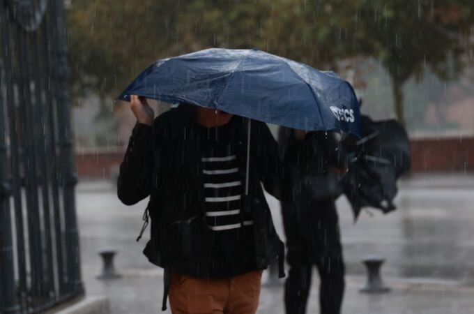 Una persona cubriéndose de la lluvia Una persona cubriéndose de la lluvia