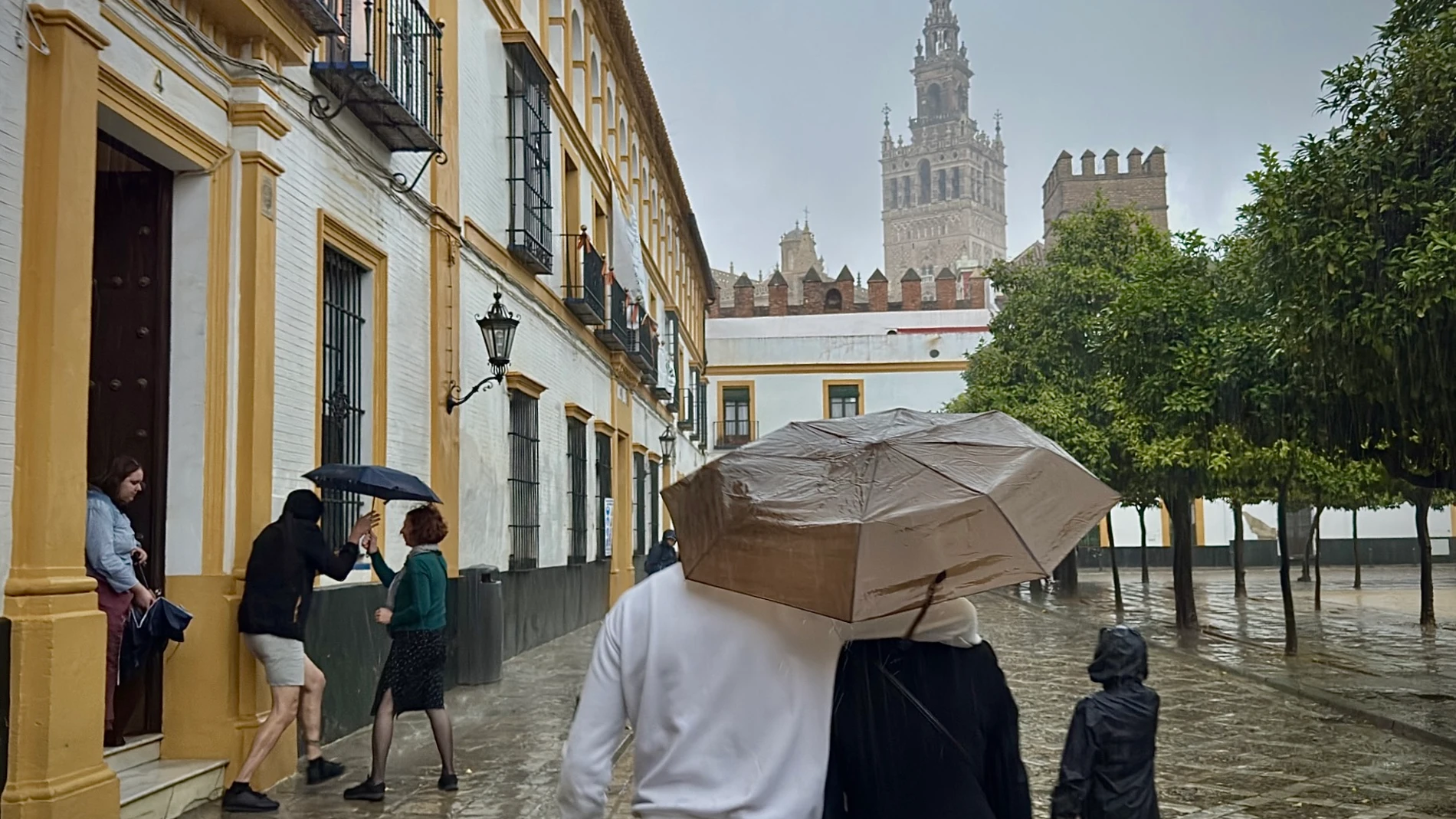 GRAFAND1471. SEVILLA, 29/10/2025.- Varias personas se resguardan de la lluvia por una calle de Sevilla.El servicio Emergencias 112 de Andalucía ha atendido ya medio millar de incidencias (502) relacionadas con el Fenómeno Meteorológico Adverso (FMA) de lluvias y tormentas que afecta especialmente a las provincias de Huelva y Sevilla y a la zona más occidental de la región andaluza. EFE/ José Manuel Vidal